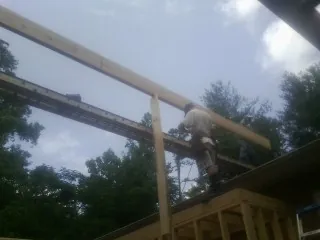 Carpenter setting a ridge beam over a new addition frame — Ice Dam Removal by Roofing Brothers in Lufkin