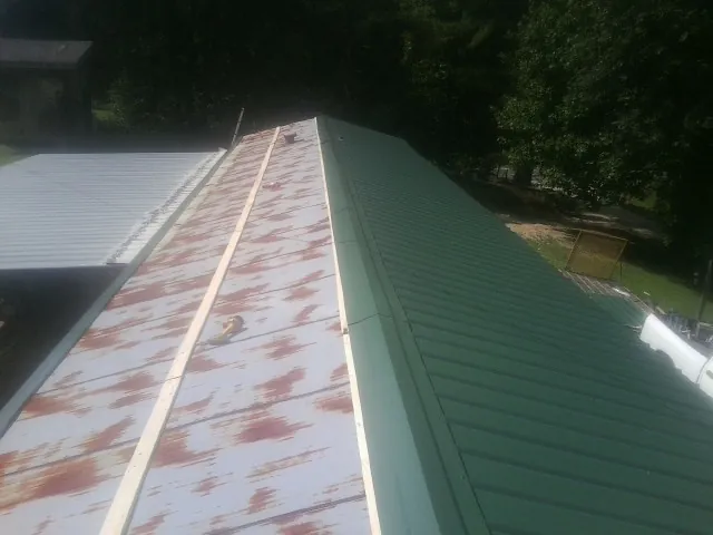 Old rusted panels beside newly installed green metal roofing — Wind Damage Roof Repair by Roofing Brothers in Lufkin