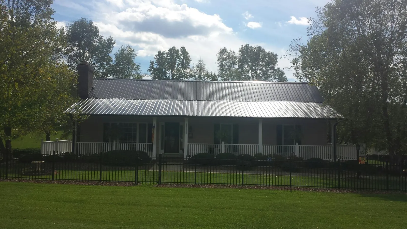 Gray metal roof on a brick ranch with a full width front porch — Gutter Guard Installation work by our crew in Lufkin